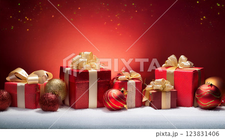 A red box with a gold bow sits on a table next to several other red boxes 123831406