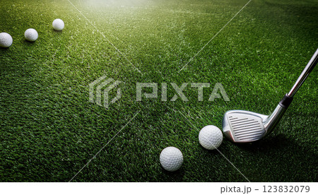 A golf course with a golf club and a few golf balls on the ground 123832079