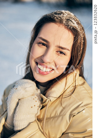 Close up portrait of cheerful smiling young woman in beige jacket with snowflakes in hair looks joyful on cold winter day. Close up portrait of cheerful smiling young woman in beige jacket with snowflakes in hair looks joyful on cold winter day. 123832620