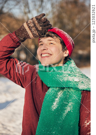 Portrait of cheerful smiling young man, dressed cozy , bright winter clothes against blurred background of sunny snowy park. Portrait of cheerful smiling young man, dressed cozy , bright winter clothes against blurred background of sunny snowy park. 123832621