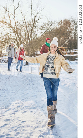 Group of young happy people, men and women, dressed stylish warm clothes, walking among snowy park on sunny winter day, sharing funny moments. Group of young happy people, men and women, dressed stylish warm clothes, walking among snowy park on sunny winter day, sharing funny moments. 123832653