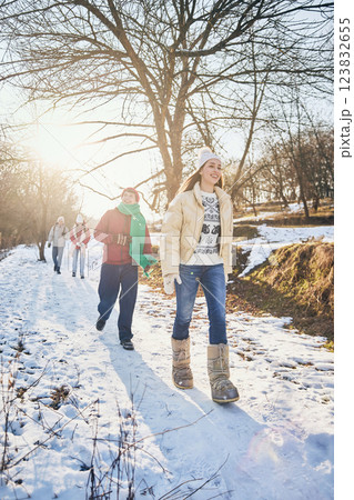 Group of young happy people, men and women, walking among snowy park on sunny winter day, dressed stylish warm clothes. Group of young happy people, men and women, walking among snowy park on sunny winter day, dressed stylish warm clothes. 123832655