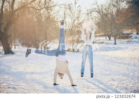 Joyful friends, man and woman, dressed warm winter sweaters, throwing snow at each other, sharing laughter in winter park. Joyful friends, man and woman, dressed warm winter sweaters, throwing snow at each other, sharing laughter in winter park. 123832674