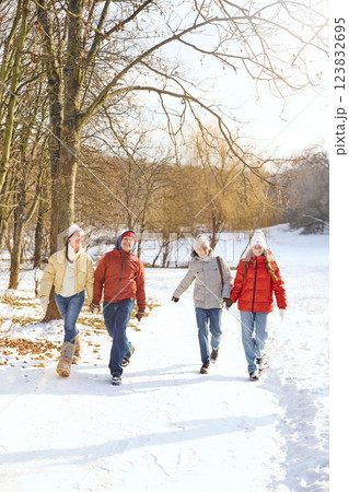 Four friends walking through snow-covered park, holding hands, sharing laughter and enjoying beautiful winter day. Four friends walking through snow-covered park, holding hands, sharing laughter and enjoying beautiful winter day. 123832695