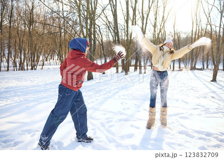 Playful couple having fun in winter park, throwing snow at each other, embracing carefree moments together. Playful couple having fun in winter park, throwing snow at each other, embracing carefree moments together. 123832709