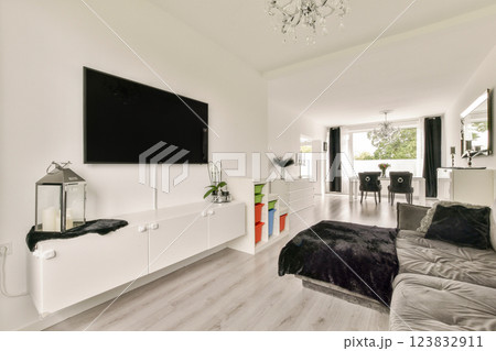 A stylish and spacious living room featuring minimalist decor, soft furnishings, and modern design elements. The bright space is complemented by natural light and elegant fixtures. 123832911