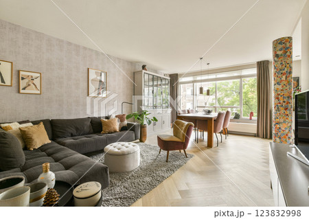 A beautifully designed modern living room showcasing elegant furniture, artistic decor, and ample natural light flowing through large windows. A beautifully designed modern living room showcasing elegant furniture, artistic decor, and ample natural light flowing through large windows. 123832998