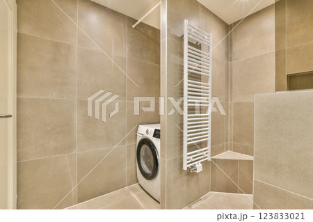 A sleek, modern laundry room featuring contemporary appliances and minimalist design elements, with harmonious brown and beige tones. A sleek, modern laundry room featuring contemporary appliances and minimalist design elements, with harmonious brown and beige tones. 123833021