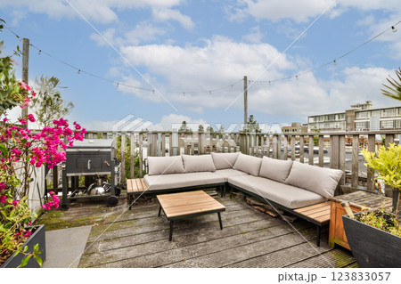 A beautifully designed rooftop lounge featuring comfy seating, modern tables, and vibrant flowers, perfect for relaxation in a serene urban environment. 123833057