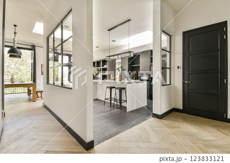 A sleek and contemporary kitchen featuring a minimalist aesthetic with dark cabinetry, light countertops, and an open layout that enhances space and functionality. 123833121