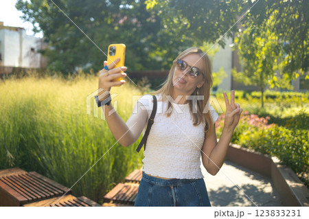 Cheerful smiling 30s lady taking selfie outdoors in city park, happy young female capturing self-portrait while enjoying walk and good day, resting outside 123833231