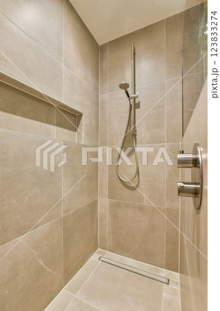 A sleek and contemporary shower featuring neutral-toned tiles and minimalist hardware, ideal for modern bathrooms. A sleek and contemporary shower featuring neutral-toned tiles and minimalist hardware, ideal for modern bathrooms. 123833274