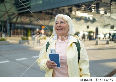 Senior female tourist in airport hold passport ticket schedule to check flight departure gate. Travel and tourism concept, people with backpack on shoulders. Senior female tourist in airport hold passport ticket schedule to check flight departure gate. Travel and tourism concept, people with backpack on shoulders. 123833275