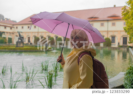 A female tourist walks around along a decorative alley decorated with many statues in a decorative park at Wallenstein Palace building in Prague in Czech Republic 123833290