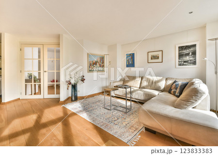 A stylish modern living room featuring a plush sofa, elegant artwork, and warm wooden flooring, creating a cozy ambiance for relaxation. 123833383