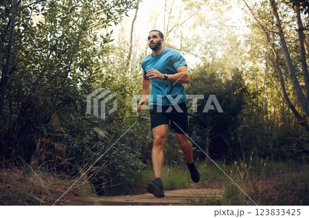 Fit man, nature run in forest and running for cardiovascular health or body wellness past green trees. Sports runner, cardio fitness training and working out doing offroad marathon workout exercise 123833425