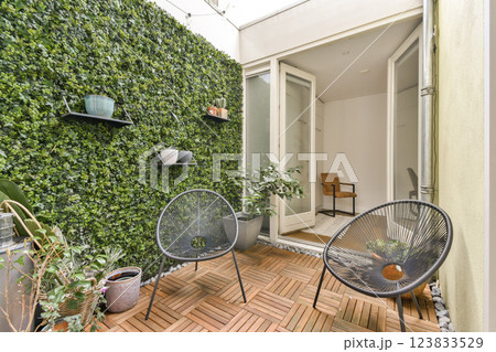 A serene indoor garden featuring lush greenery, stylish seating, and wooden flooring, ideal for relaxation and aesthetics. 123833529