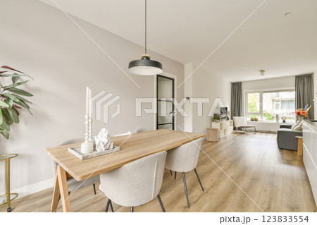 Charming modern interior featuring a stylish dining area with a minimalist table, elegant chairs, and a bright window view that enhances the ambiance. 123833554
