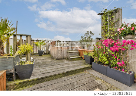 A tranquil rooftop garden featuring various plants and flowers, offering a perfect escape from the urban hustle. The wooden deck adds to the serene atmosphere. 123833615