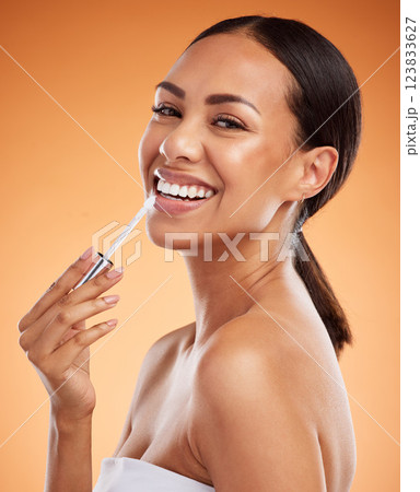 Beauty, skincare and cosmetics with a model black woman using lipstick or lip balm on her mouth in studio on an orange background. Makeup, face and lips with a young female applying a treatment Beauty, skincare and cosmetics with a model black woman using lipstick or lip balm on her mouth in studio on an orange background. Makeup, face and lips with a young female applying a treatment 123833627
