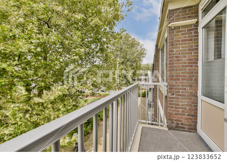 A bright balcony overlooking lush green trees, creating a serene and peaceful atmosphere. Ideal for relaxation and enjoying nature. 123833652