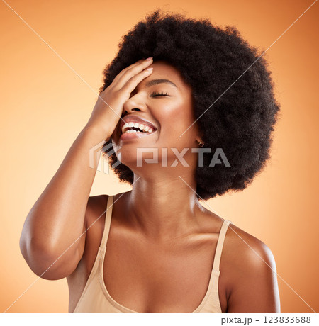 Beauty, skincare and black woman with afro hair touching face with makeup, cosmetics and laughing while happy with cosmetology treatment. African female model against brown background for dermatology 123833688