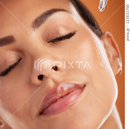 Oil, skincare and woman with product for facial health against an orange studio background. Face of a model with a liquid serum for beauty, cleaning of skin and essential oil from dermatology Oil, skincare and woman with product for facial health against an orange studio background. Face of a model with a liquid serum for beauty, cleaning of skin and essential oil from dermatology 123833700