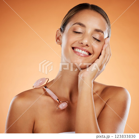 Happy woman in studio, skincare stone roller tool for facial massage and luxury cosmetic product. Pink rose quartz gua sha, smooth soft face and young natural beauty in wellness treatment in studio Happy woman in studio, skincare stone roller tool for facial massage and luxury cosmetic product. Pink rose quartz gua sha, smooth soft face and young natural beauty in wellness treatment in studio 123833830