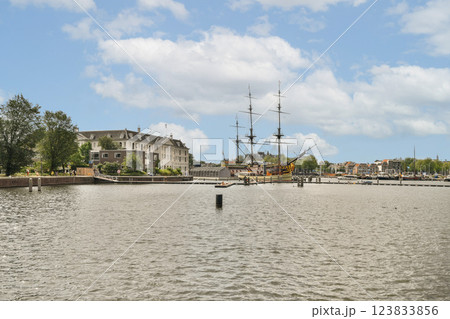 A picturesque river scene featuring historical ships alongside modern buildings, framed by lush greenery and a vibrant sky. A picturesque river scene featuring historical ships alongside modern buildings, framed by lush greenery and a vibrant sky. 123833856