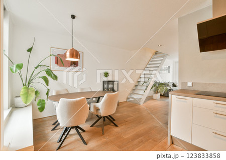A contemporary living space featuring a well-lit room with stylish furniture, indoor plants, and a staircase, exuding comfort and elegance. 123833858