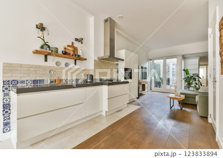 A stylish modern kitchen featuring sleek cabinetry, wooden flooring, and large windows that bring in natural light, creating an open and inviting atmosphere. A stylish modern kitchen featuring sleek cabinetry, wooden flooring, and large windows that bring in natural light, creating an open and inviting atmosphere. 123833894