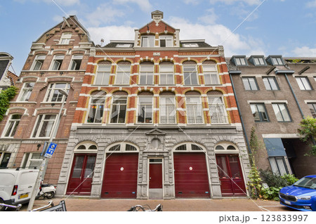 Elegant historic building showcasing intricate brickwork and arched windows, set against a clear blue sky in an urban landscape. Elegant historic building showcasing intricate brickwork and arched windows, set against a clear blue sky in an urban landscape. 123833997