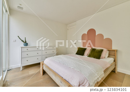A serene and stylish bedroom featuring a wooden bed, soft pastel colors, and minimalistic decor elements, emphasizing comfort and tranquility. 123834101