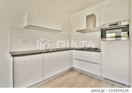 A sleek and contemporary kitchen design featuring white cabinetry, minimalistic appliances, and a clean aesthetic that enhances functionality and style. A sleek and contemporary kitchen design featuring white cabinetry, minimalistic appliances, and a clean aesthetic that enhances functionality and style. 123834228