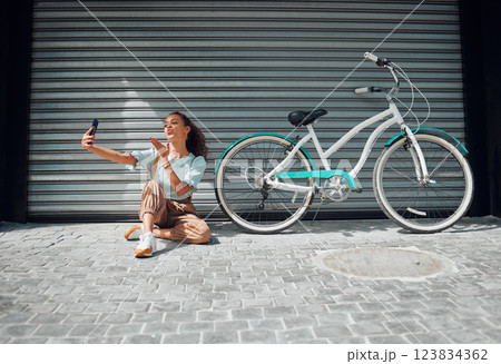 Bicycle, street and woman taking a selfie in a city blowing a kiss in photo or pictures in summer outdoors. Freedom, bike and young girl creating phone content for social media followers in holidays Bicycle, street and woman taking a selfie in a city blowing a kiss in photo or pictures in summer outdoors. Freedom, bike and young girl creating phone content for social media followers in holidays 123834362