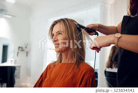 Hairdresser, flat iron and woman in salon for hair appointment with happy customer. Stylist using hair straightener on client in beauty salon or hair shop for straight hair, heat treatment and style 123834541