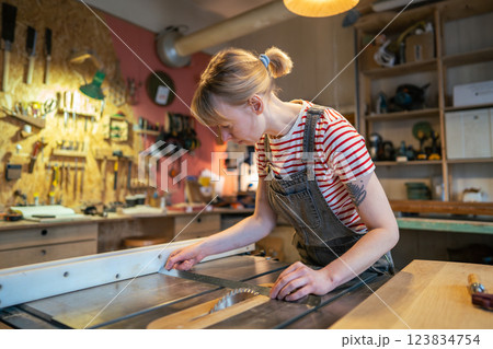 Woman carpenter inspecting wooden beam straightness with ruler before cutting with saw in workshop Woman carpenter inspecting wooden beam straightness with ruler before cutting with saw in workshop 123834754