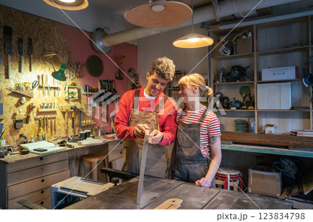 Laughing satisfied man joiner praising female newbie for quality woodwork. Joyful mentorship Laughing satisfied man joiner praising female newbie for quality woodwork. Joyful mentorship 123834798