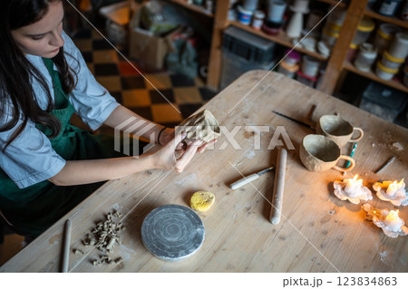Woman potter hands molding cups with pattern on wooden table in pottery workshop. Artisan school 123834863