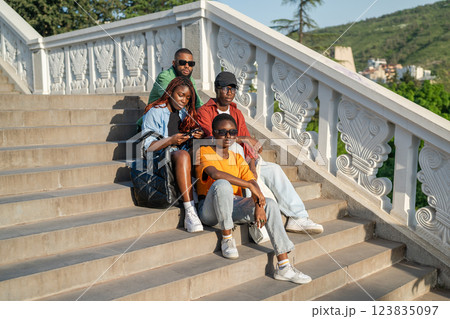 African American friends on stairs, looking at phones, preparing for travel adventure together 123835097