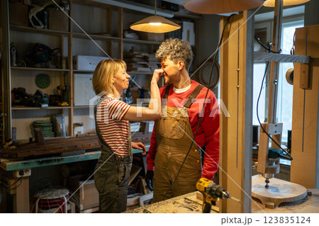 Cheerful family of carpenters having fun and joy in workshop, playful moment during work break 123835124