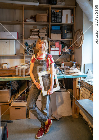 Relaxed thoughtful woman carpenter take break holding piece wooden handmade product in joiner shop. Relaxed thoughtful woman carpenter take break holding piece wooden handmade product in joiner shop. 123835168