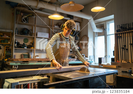 Carpentry workshop, craftsman master working. Man uses circular woodworking machine. 123835184