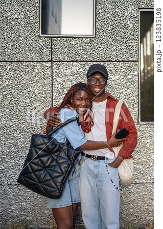 Happy African American siblings cuddlling, look at camera with smiles near wall. Weekend stroll Happy African American siblings cuddlling, look at camera with smiles near wall. Weekend stroll 123835198