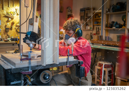 Carpentry workshop craftsman master working. Manual wood milling guy holds tool controlling process Carpentry workshop craftsman master working. Manual wood milling guy holds tool controlling process 123835262