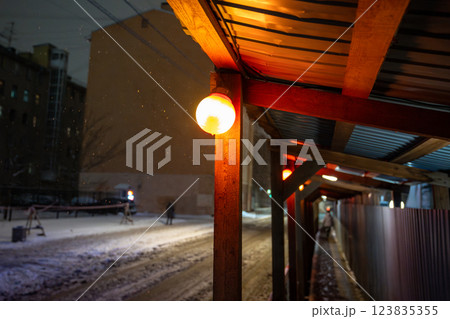 Snowstorm through construction site, canopy with lamps casting warm light on fall snow at night Snowstorm through construction site, canopy with lamps casting warm light on fall snow at night 123835355