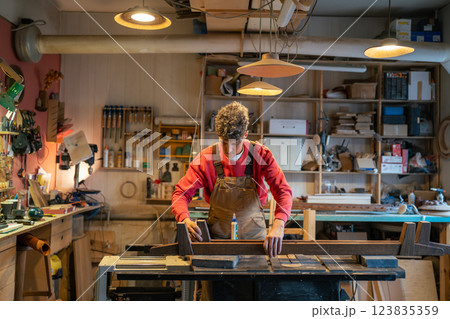 Skilled handyman carefully assemble bed base, focusing on precise measurements. Furniture production Skilled handyman carefully assemble bed base, focusing on precise measurements. Furniture production 123835359
