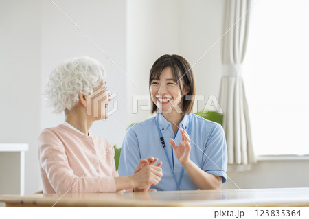 笑顔で会話をする介護スタッフとシニア女性 123835364