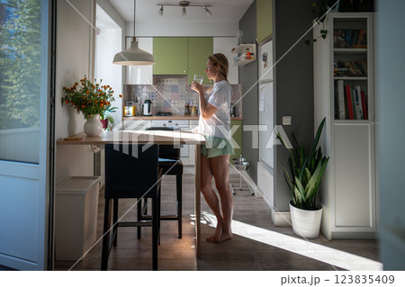 Woman drinking cool water in kitchen, refreshing start to morning. Diet balance, energizing morning Woman drinking cool water in kitchen, refreshing start to morning. Diet balance, energizing morning 123835409