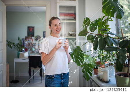 Happy middle aged woman enjoy relaxing time alone with mug hot tea takes break from household chores Happy middle aged woman enjoy relaxing time alone with mug hot tea takes break from household chores 123835411